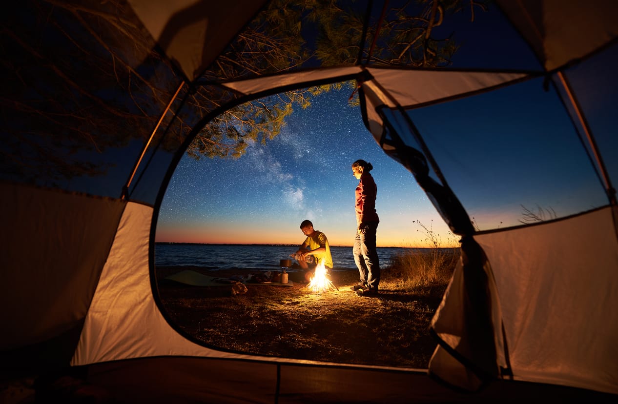 Resting in the tent Resting in tent and burning campfire on sea shore near forest