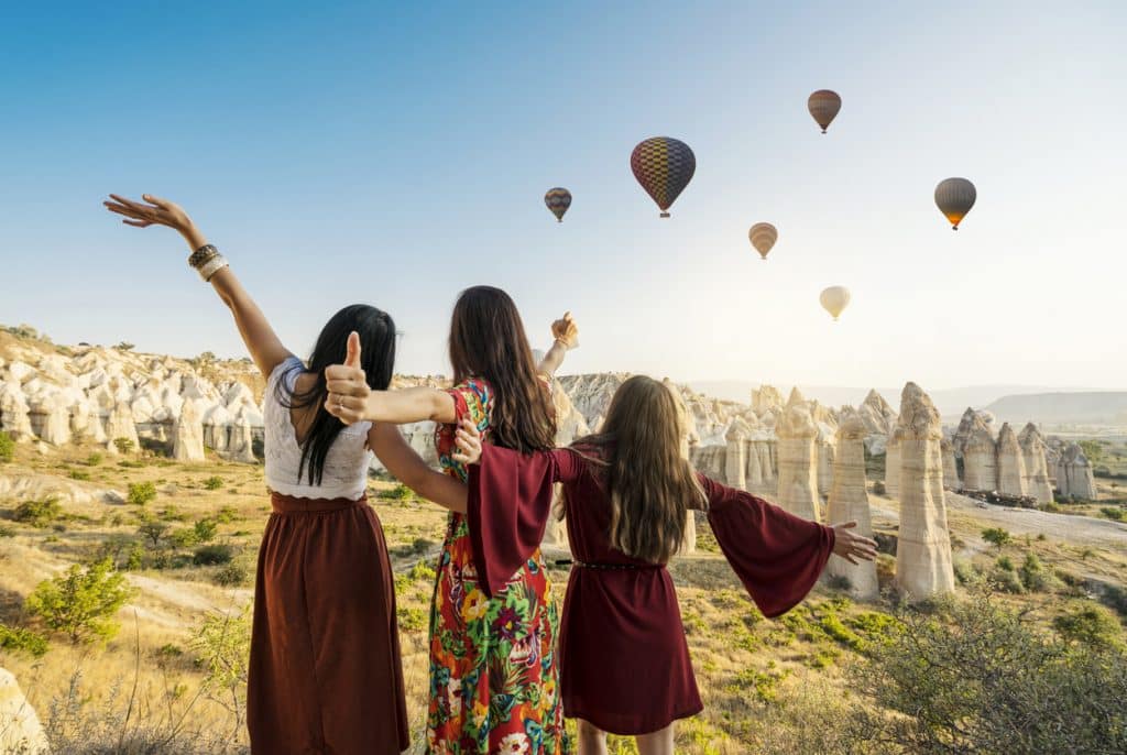 Traveling women looking at air balloons in sky in Cappadocia valley.